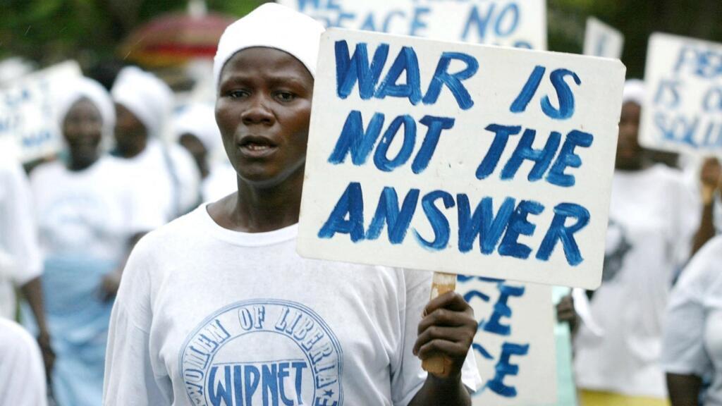 Une femme libérienne, membre de l'organisation Liberian Women Mass Actions for Peace, défile à Monrovia avec une pancarte clamant « La guerre n'est pas la réponse », le 28 août 2003, alors que se termine la deuxième guerre civile libérienne.
