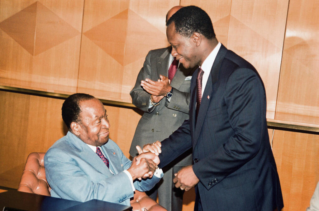Photographie d'archive montrant le président ivoirien Félix Houphouët-Boigny (à gauche) tenant les mains d'Alassane Ouattara (à droite), son Premier ministre à l'époque, à Abidjan, en juillet 1991.