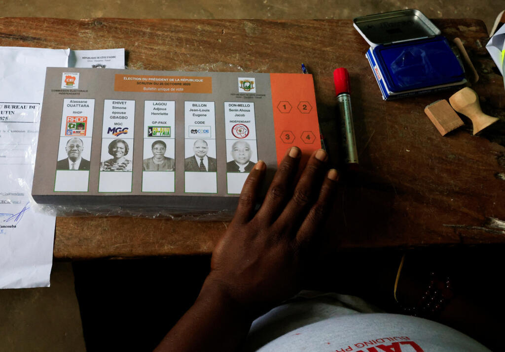 Un agent électoral attend de distribuer les bulletins de vote aux électeurs lors de l'élection présidentielle, dans un bureau de vote à l'intérieur d'une école, à Abidjan, en Côte d'Ivoire, le 25 octobre 2025.