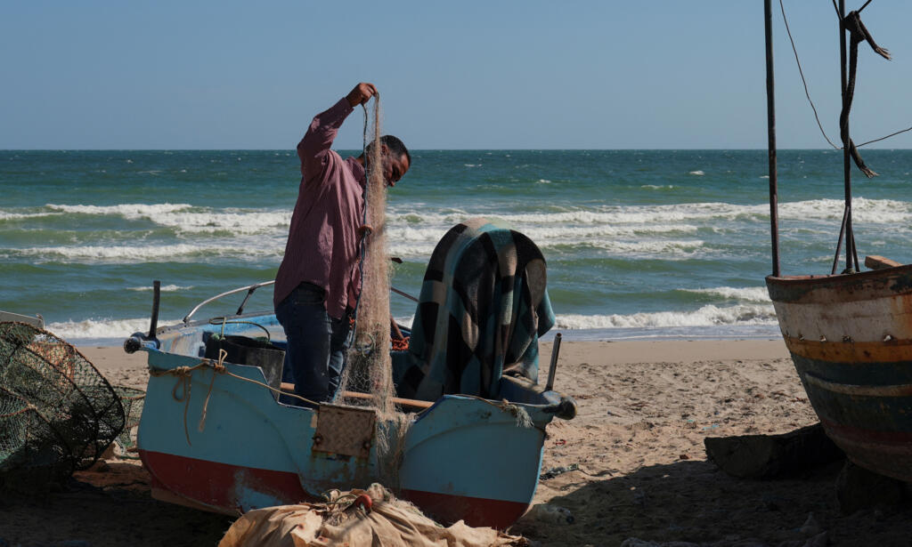 Le pêcheur Sassi Alaya prépare son filet de pêche sur la plage de Gabès, en Tunisie, le 16 octobre 2025, quelques jours après le début des manifestations contre la pollution causée par le complexe du Groupe chimique tunisien.