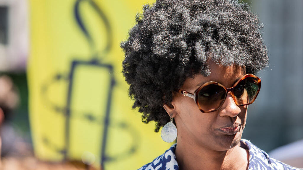 Ketty Nivyabandi, secrétaire générale d'Amnesty International Canada, elle-même réfugiée, se tient devant une pancarte pendant la manifestation. À l'occasion de la Journée mondiale des réfugiés, Amnesty International Canada et Human Rights Watch ont organisé une manifestation devant le bureau du Premier ministre à Montréal pour demander la fin de la détention forcée des réfugiés et des demandeurs d'asile au Québec, le 20 juin 2022.