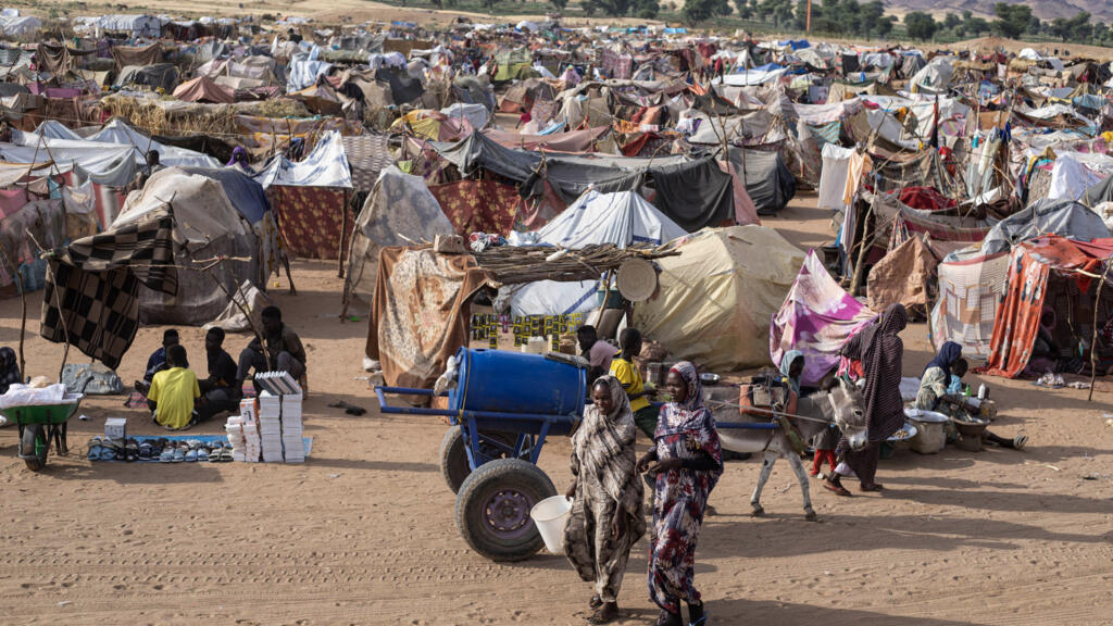 Des Soudanais déplacés, ayant fui El-Fasher après la chute de la ville aux mains des FSR, marchent dans le camp d'Um Yanqur, situé à l'extrémité sud-ouest de Tawila, dans la région du Darfour, à l'ouest du Soudan, le 3 novembre 2025.