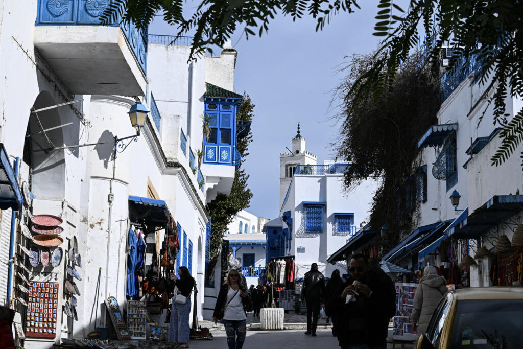 Des personnes marchent dans une rue du village de Sidi Bou Said le 27 janvier 2026, après que la région a été frappée par la tempête Harry. Les autorités ont ordonné l'évacuation de plusieurs maisons menacées d'effondrement dans ce village touristique.